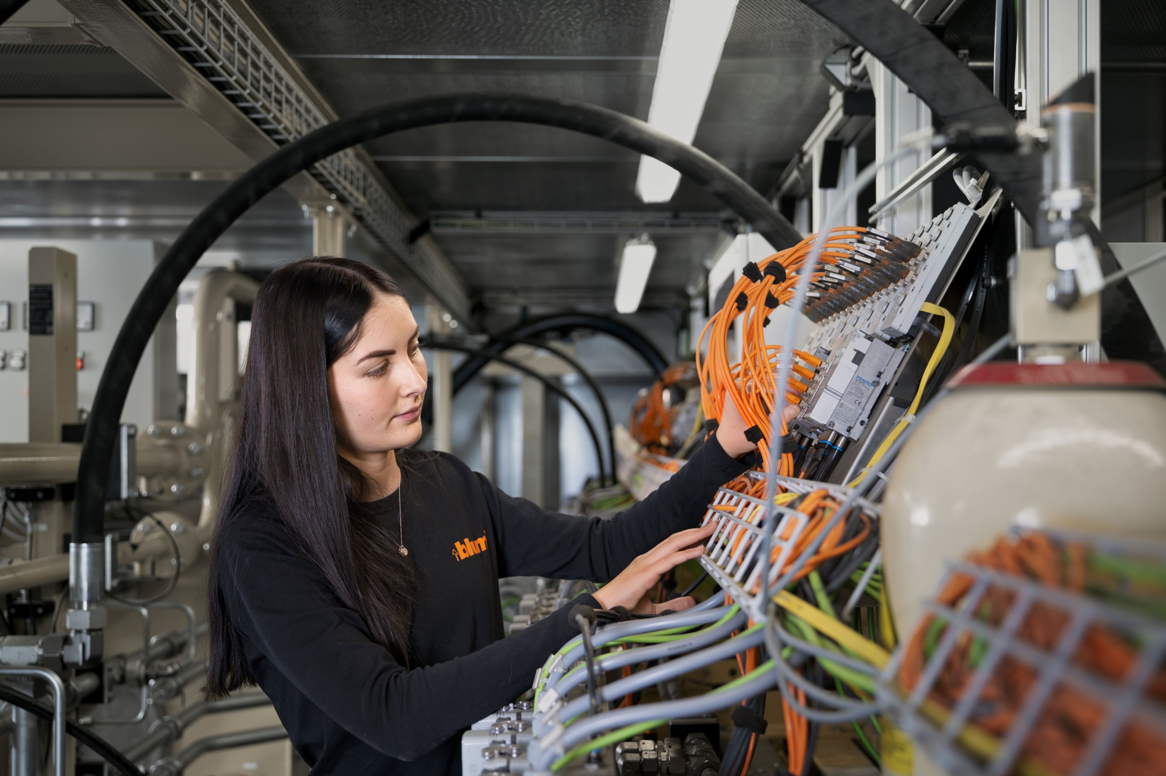 Auszubildende in der Maschinenbautechnik arbeiten an einer automatisierten Produktionsanlage und prüfen mechanische, pneumatische und sensorische Komponenten direkt in der Fertigung.