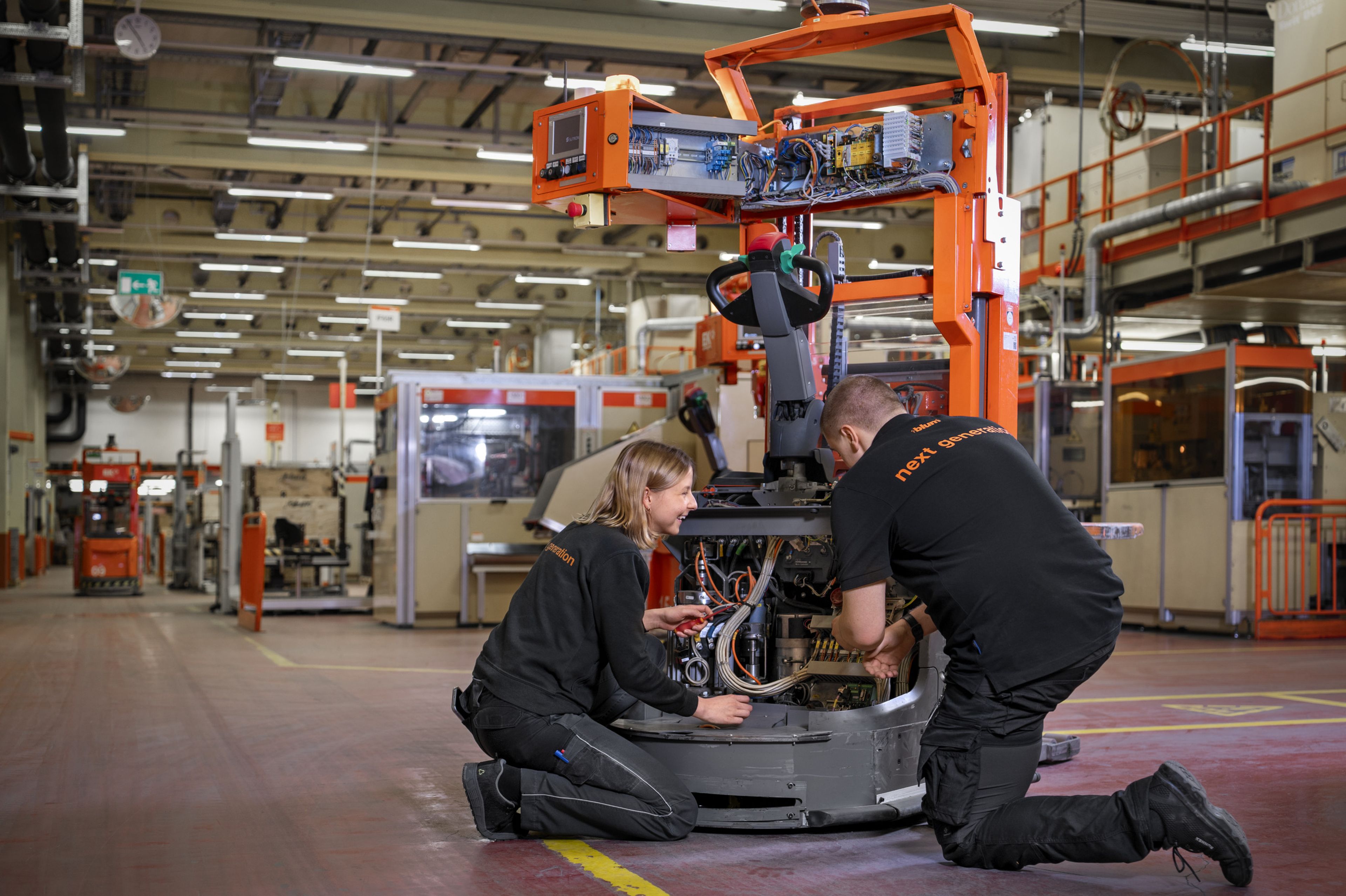 Auszubildende arbeiten an einer Fördertechnik‑Einheit im Produktionsumfeld und montieren sowie prüfen mechanische, elektrische und pneumatische Komponenten