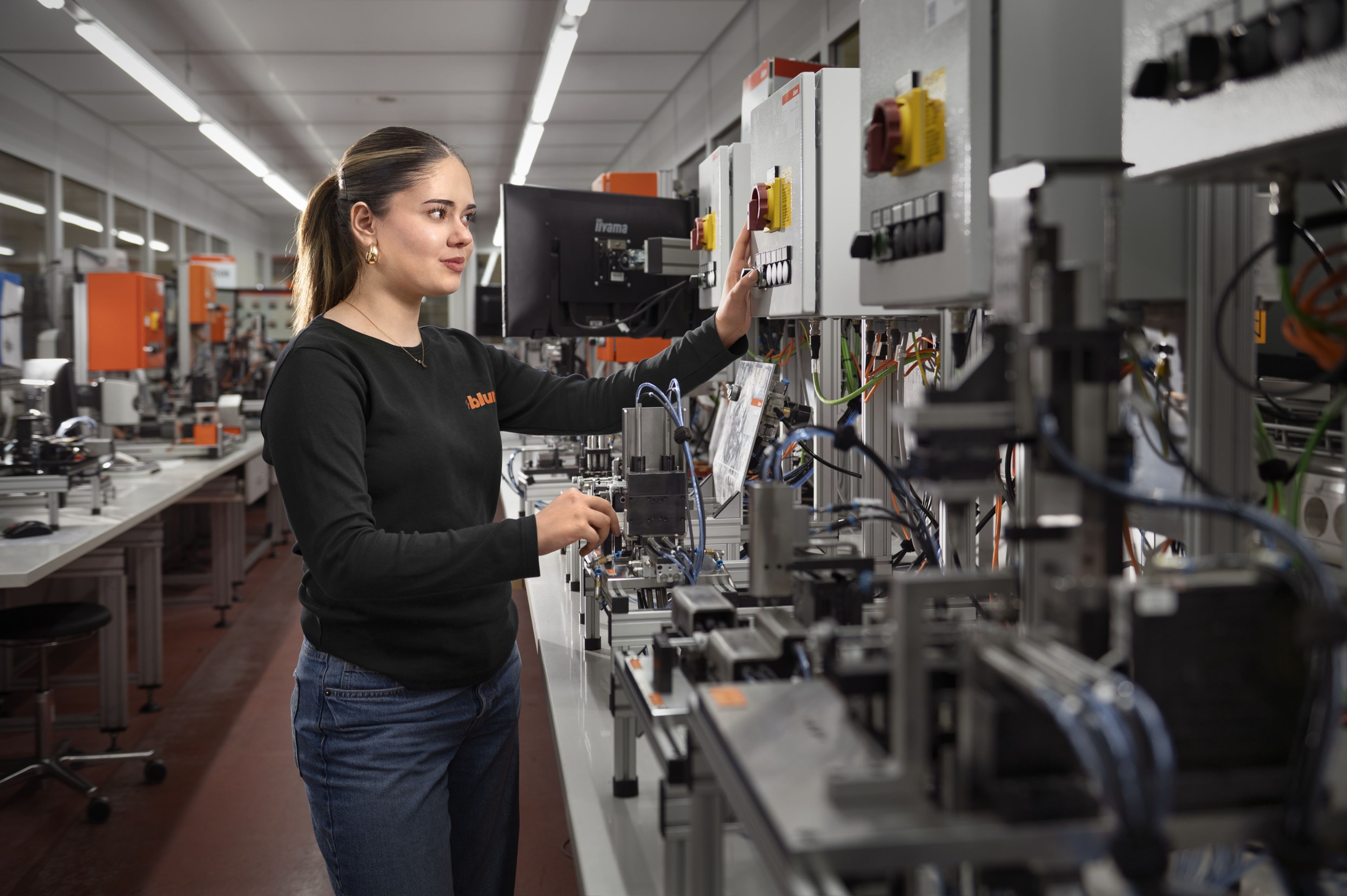 Eine Auszubildende in der Ausbildung Prozesstechnik bei Blum prüft ein Produkt in der Qualitätssicherung und kontrolliert Qualitätsmerkmale im laufenden Produktionsprozess.