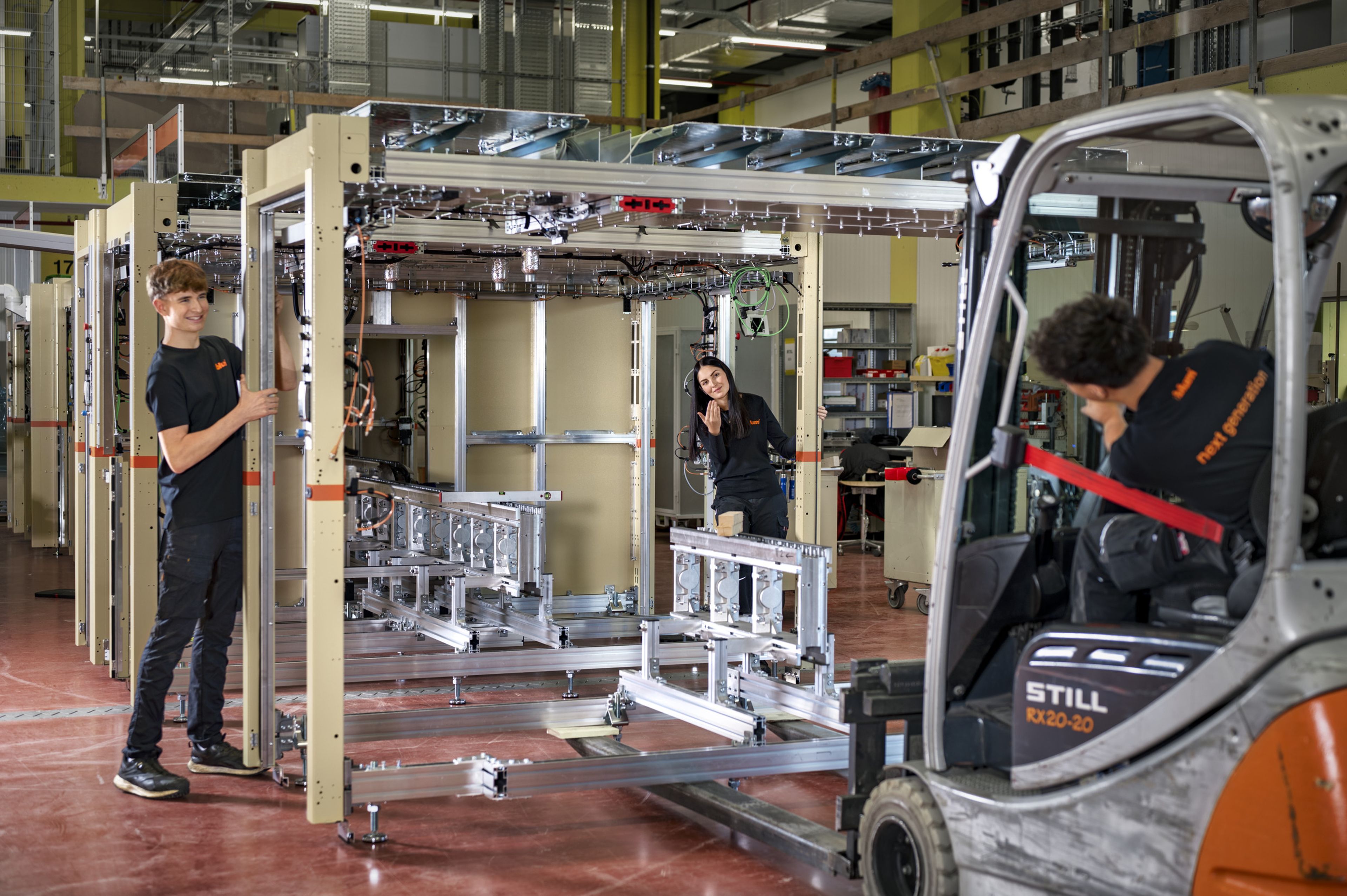 Anlagenaufbau in der Maschinenbautechnik mit Unterstützung eines Staplers zum sicheren Transport und Positionieren von Maschinenteilen.