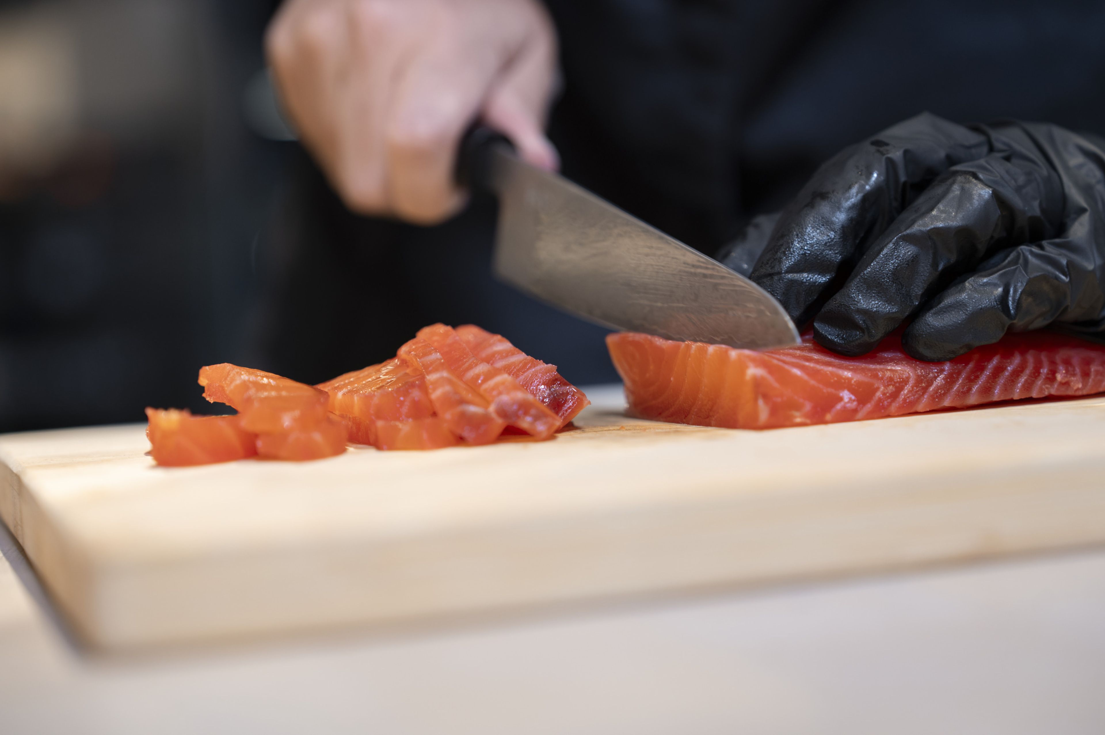 Ein Fischfilet wird mit einem Messer in dünne Scheiben geschnitten