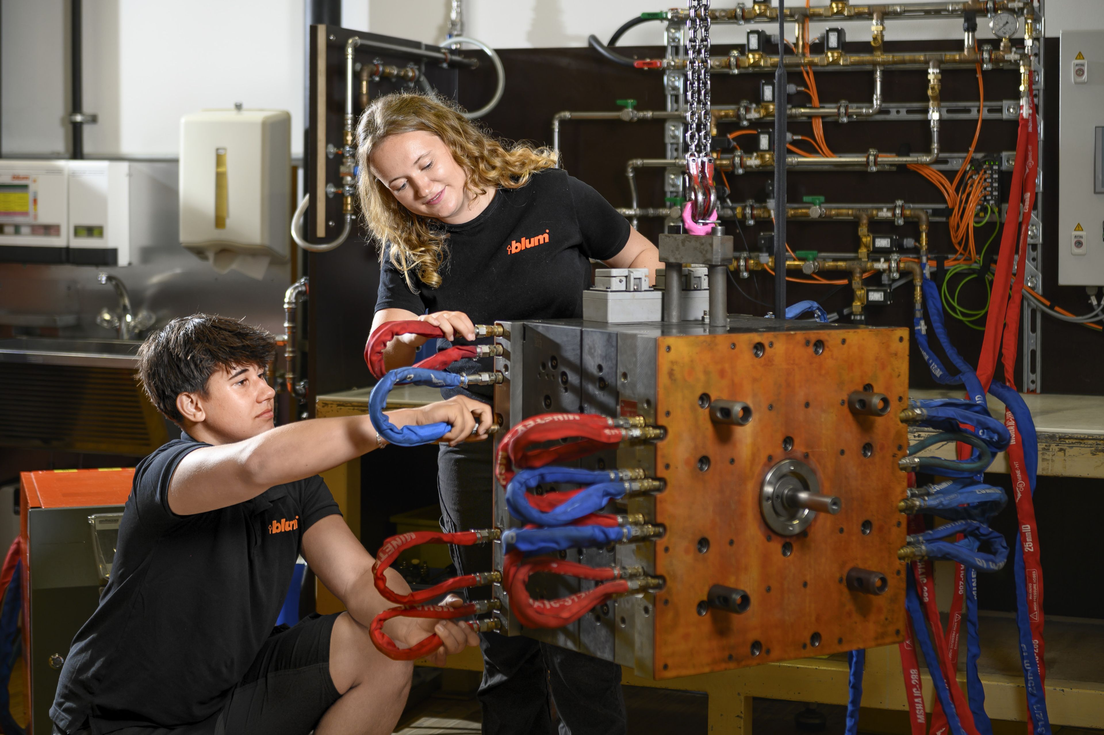 Zwei Lehrlinge der Werkzeugbautechnik bei Blum arbeiten an einem Spritzgusswerkzeug. In der Ausbildung Werkzeugbautechnik mit Schwerpunkt Prozess- und Projektmanagement lernen angehende Fachkräfte die Herstellung, Wartung, Optimierung und Instandsetzung von Stanz-, Spritzguss- und Druckgusswerkzeugen.
