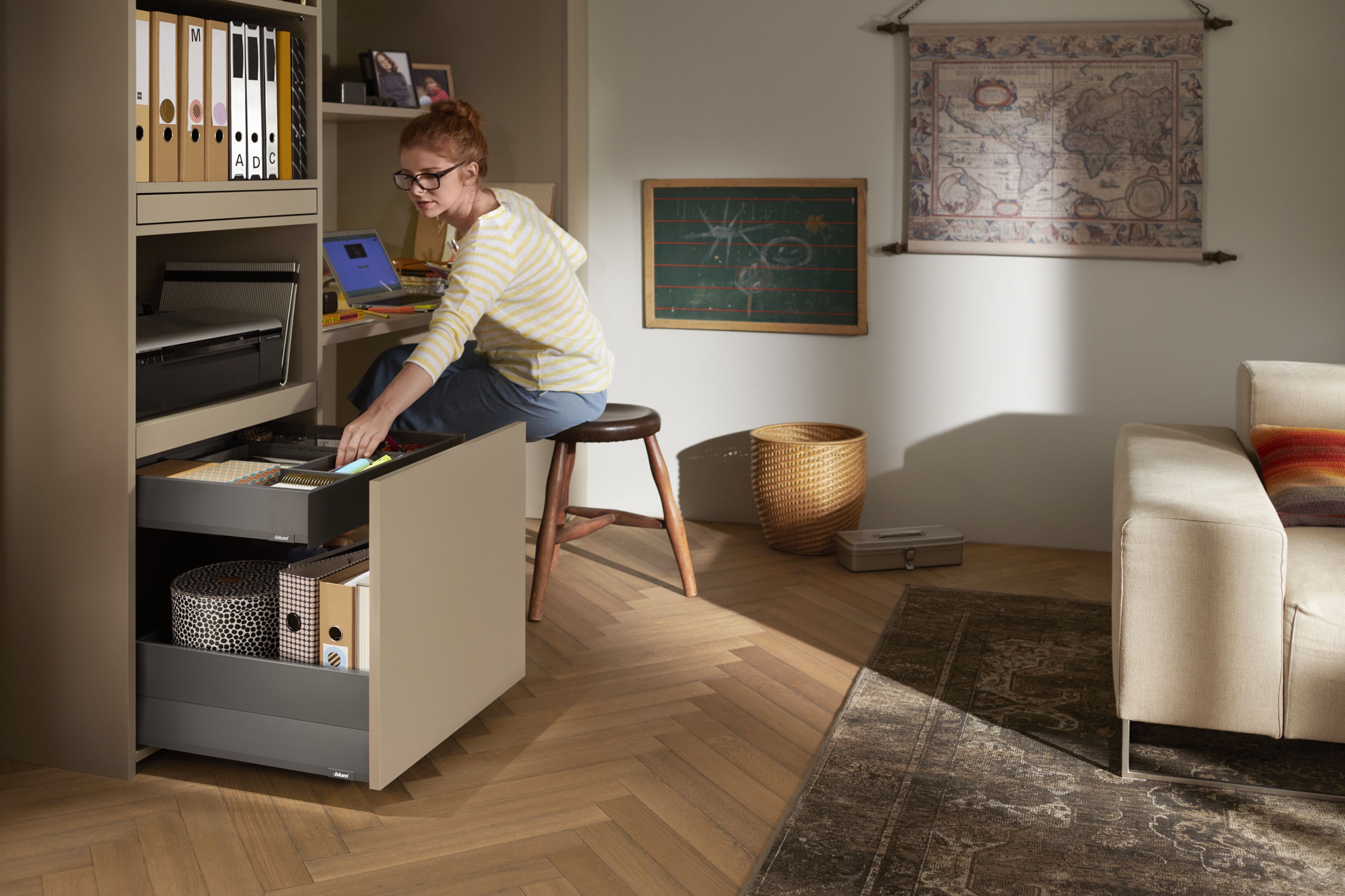  Eine Frau entnimmt etwas aus einer Innenschublade in einem Büroschrank. 