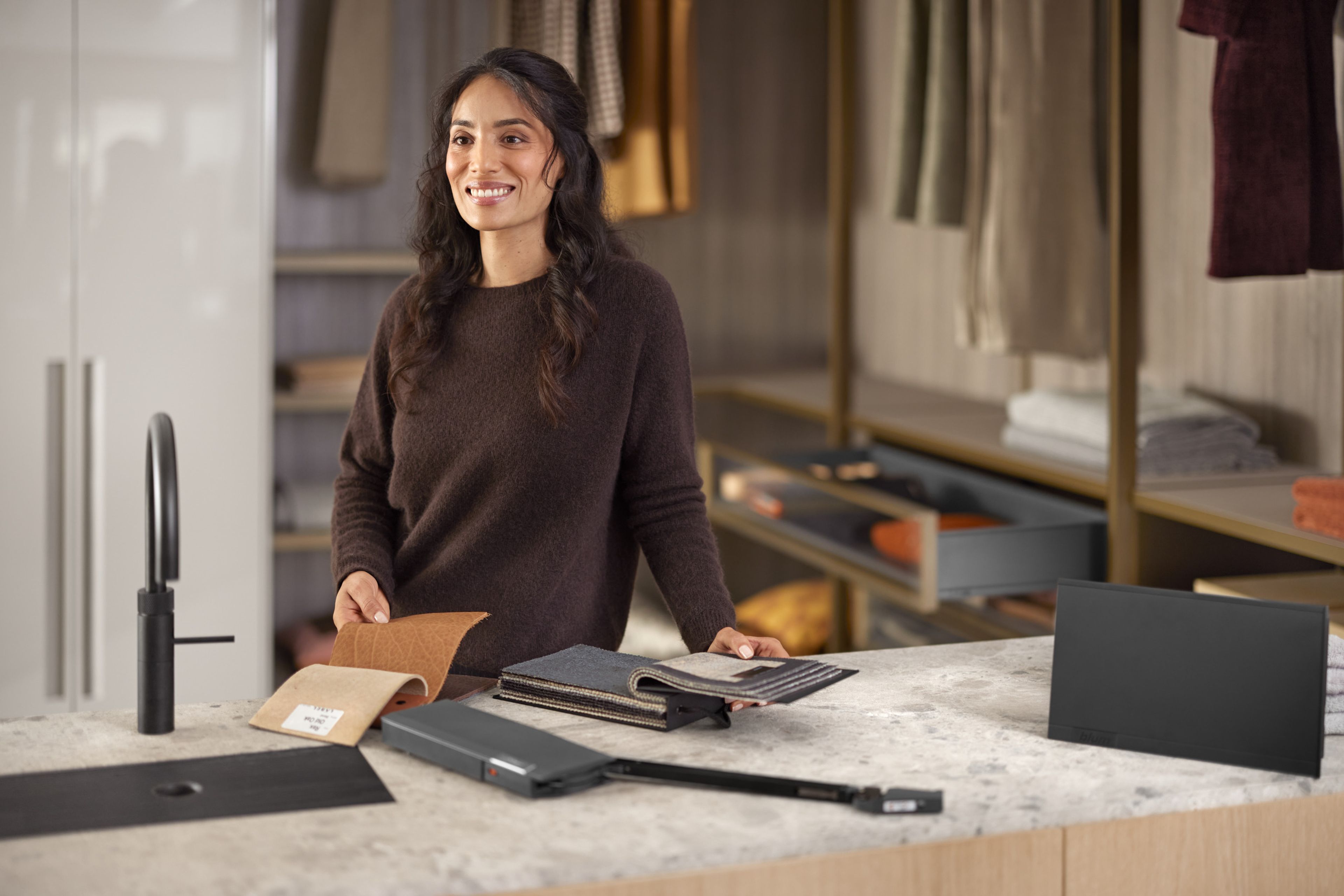 A woman stands at a table with a selection of material samples, a lift system in black and a cover cap