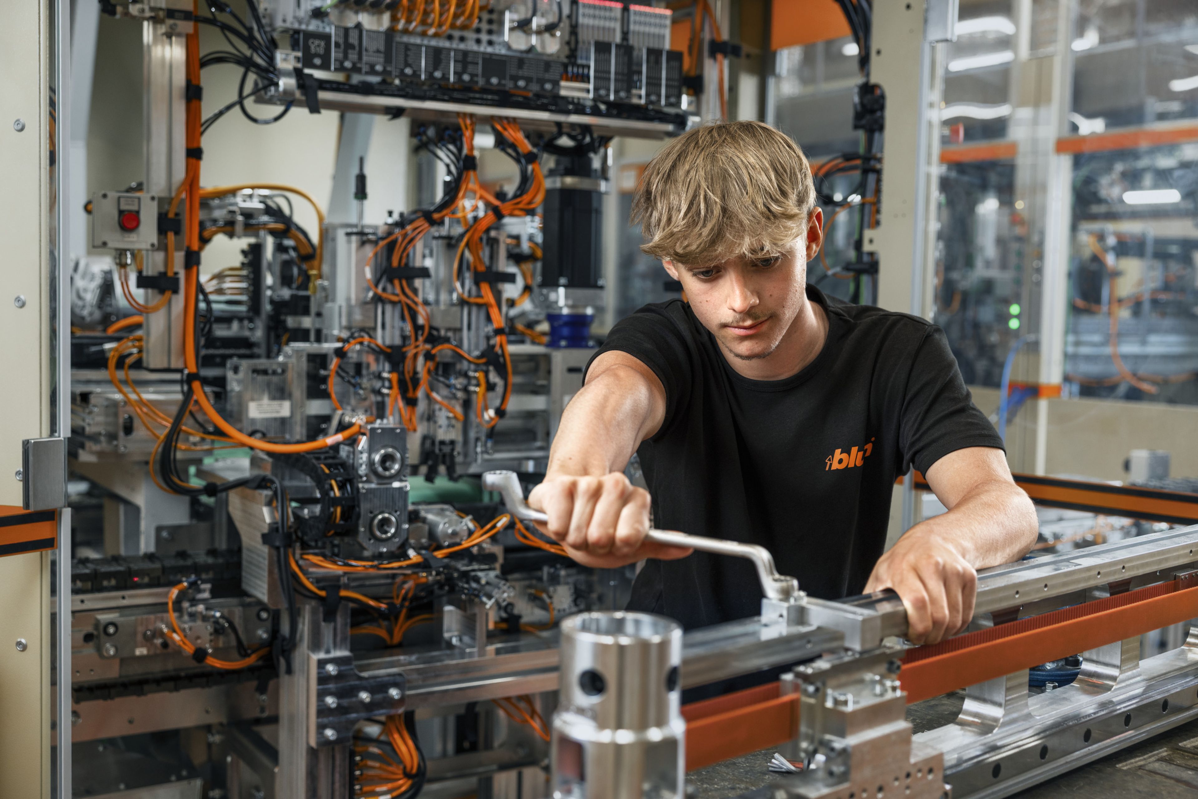 Das Bild zeigt einen Maschinenbautechnik-Lehrling der gerade  einen Greifer einer Anlage repariert. 