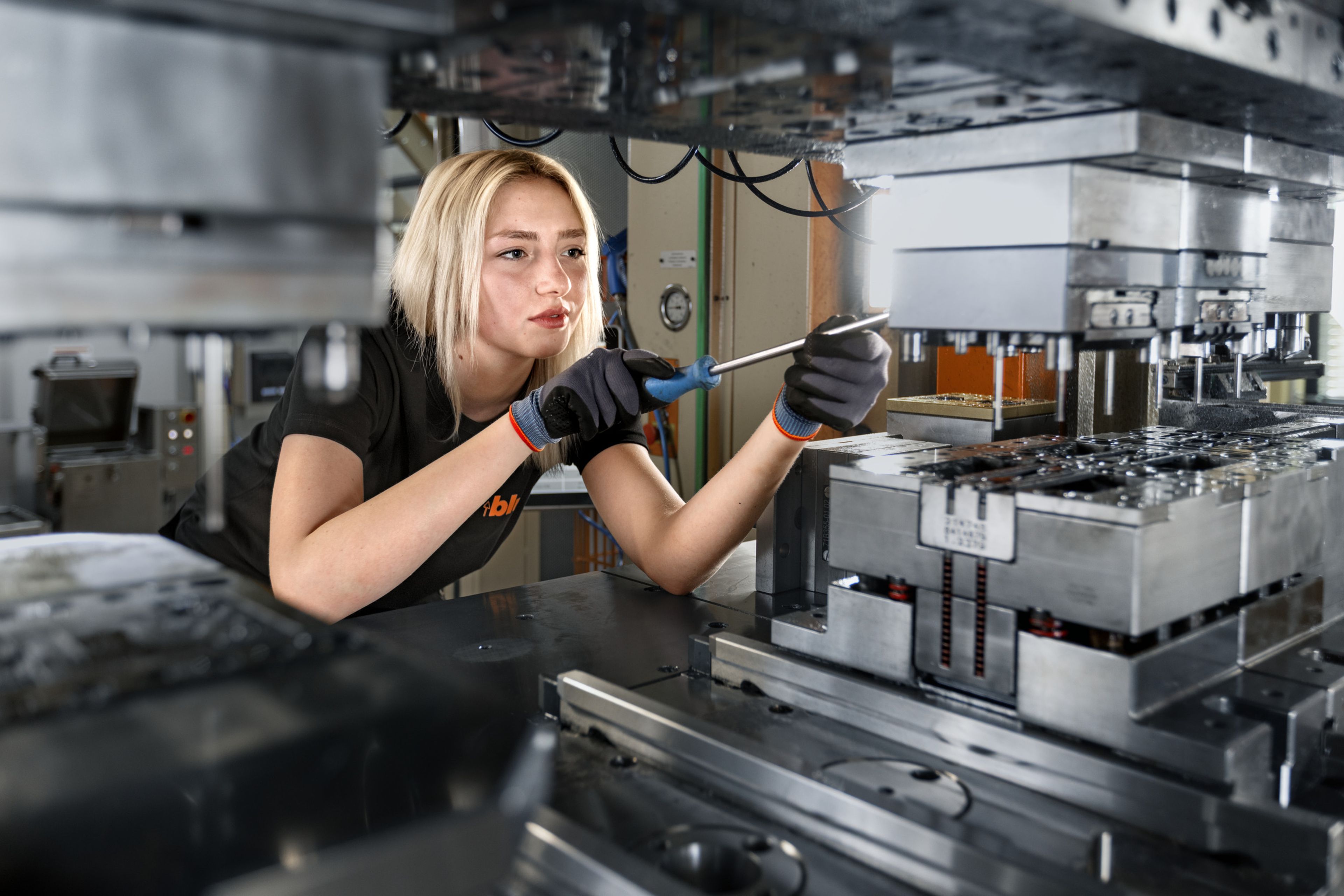 Das Bild zeigt wie ein weiblicher Lehrling in der Prozesstechnik eine Stanze rüstet. 