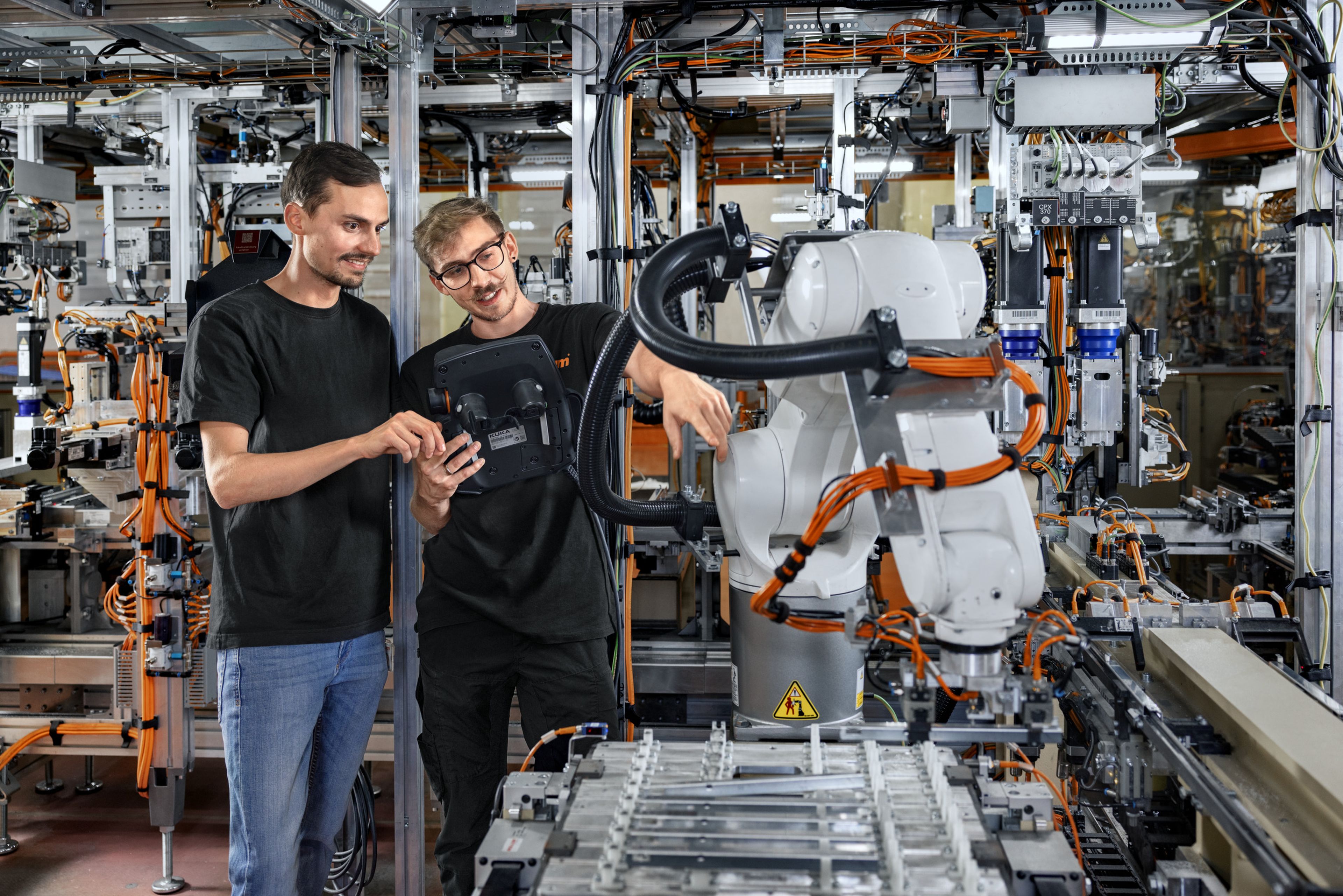 Das Bild zeigt einen Lehrling der gerade die Roboterfahr eines Roboters neu einstellt.