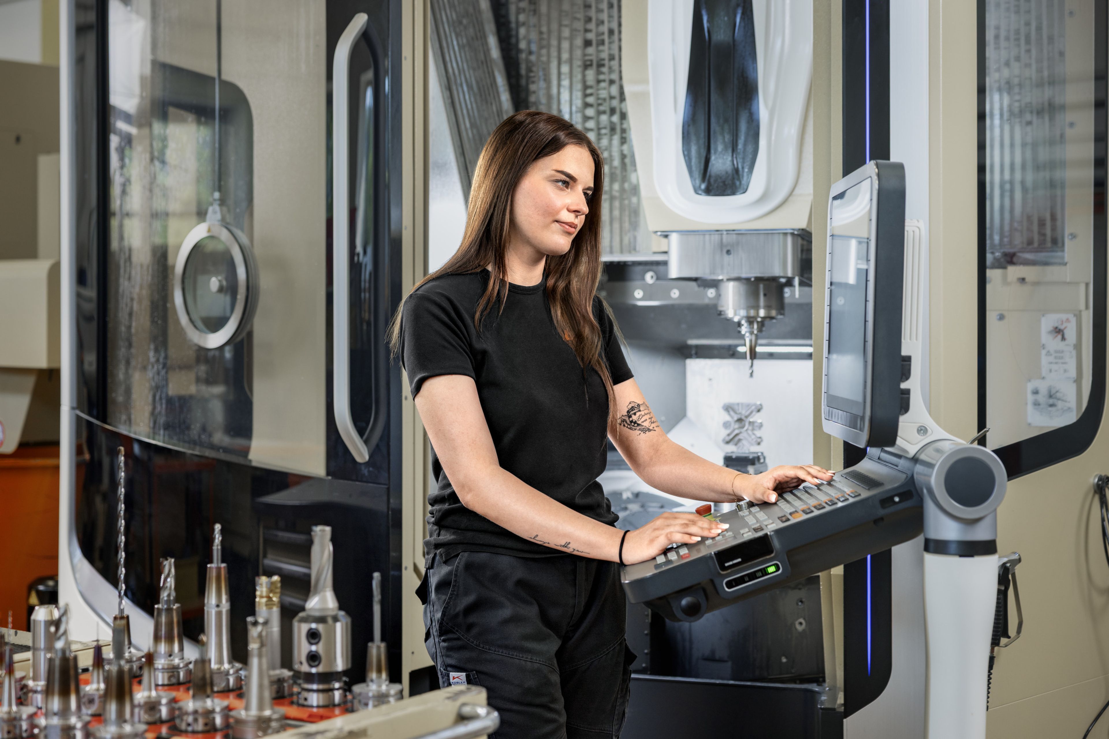 Das Bild zeigt einen Lehrling in der Zerspanungstechnik von Blum der gerade an der CNC-Maschine programmiert. 