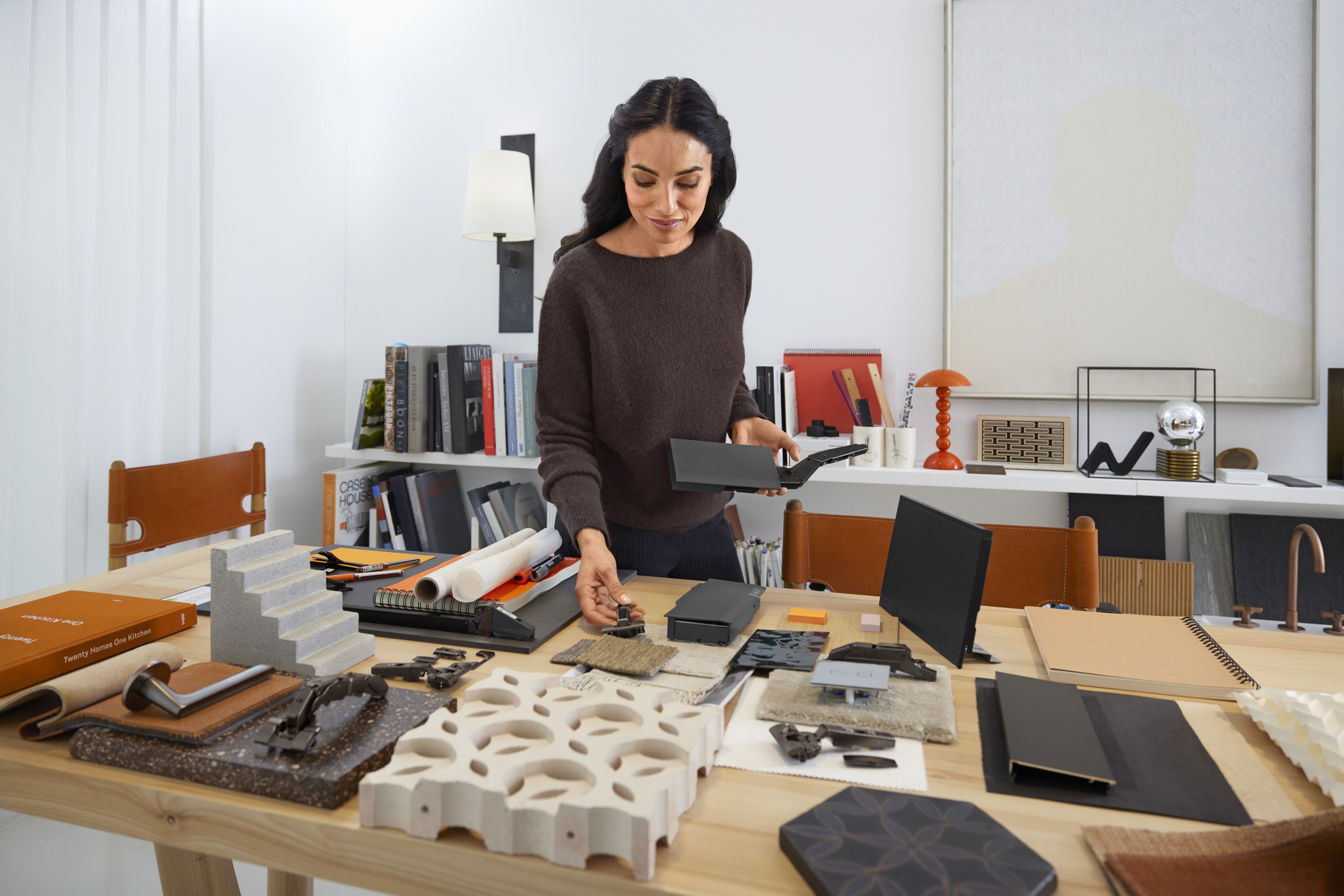 A woman stands at a table and looks at material and colour samples