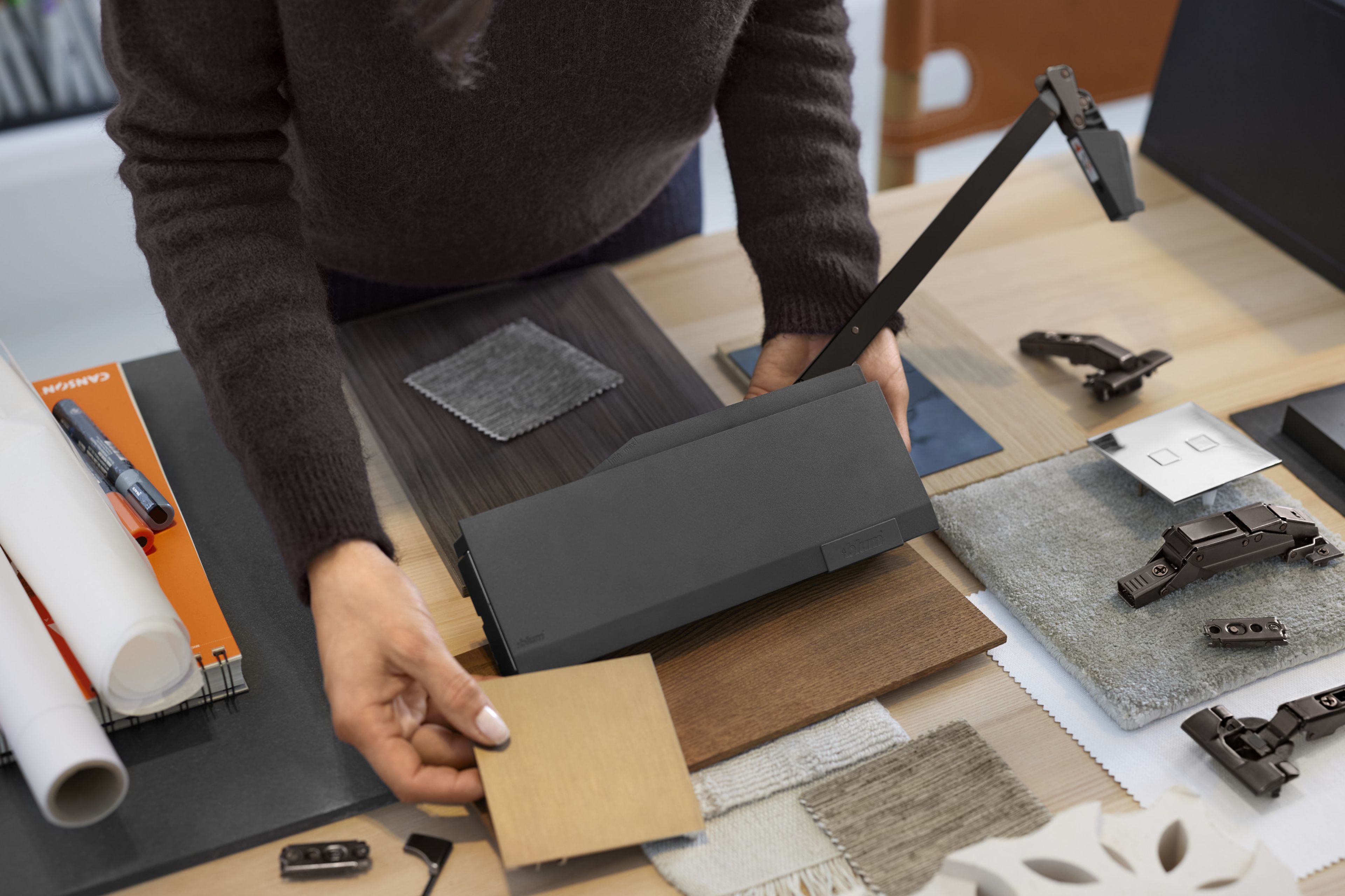 A woman holds a material sample against a dark fitting