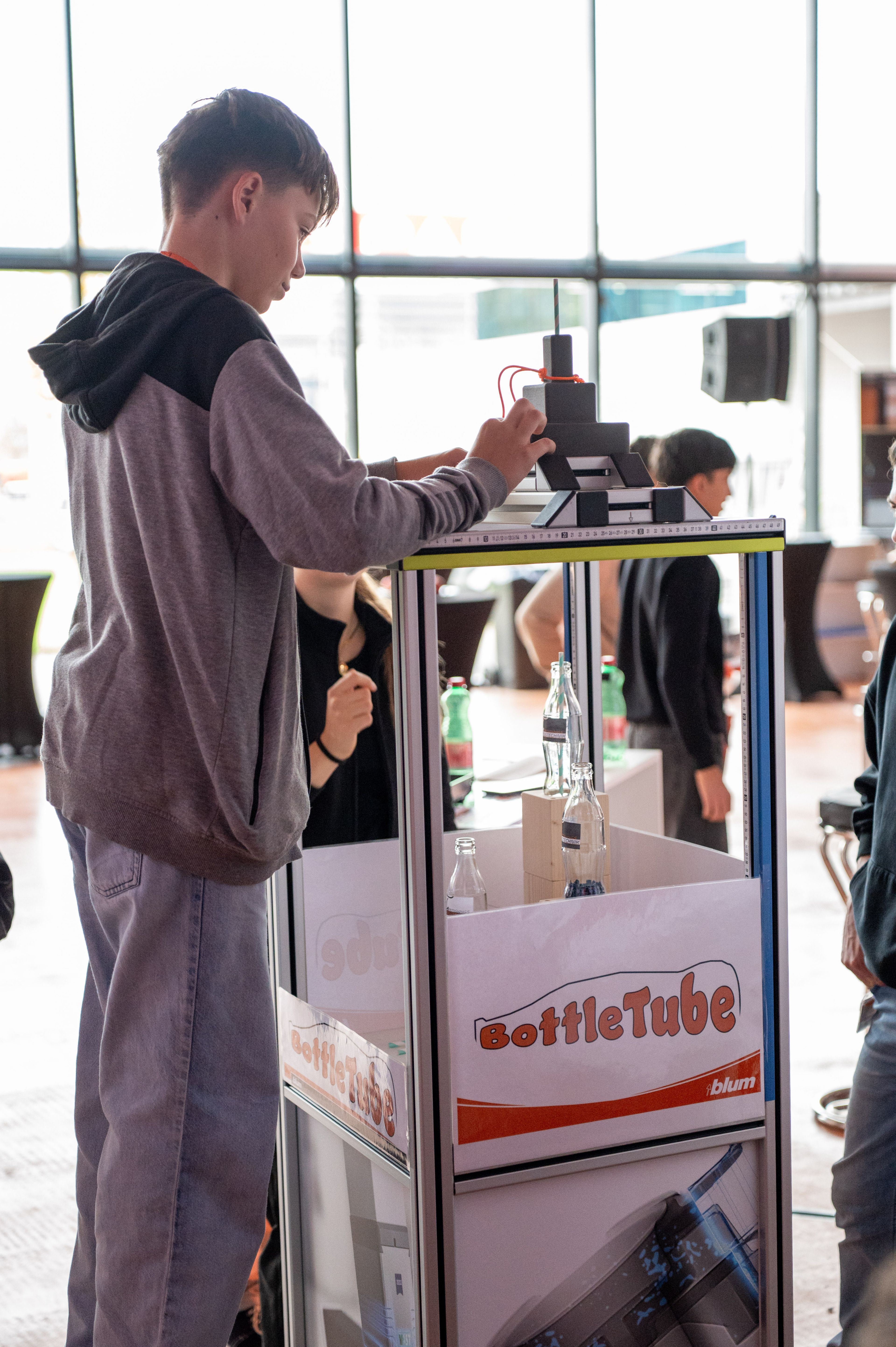 Eine Person erkundet auf der Ausbildungsmesse von Blum ein technisches Demonstrationsmodell. Praxisstationen vermitteln Einblicke in technische Ausbildungsberufe, moderne Technologien und die Ausbildung bei Blum.