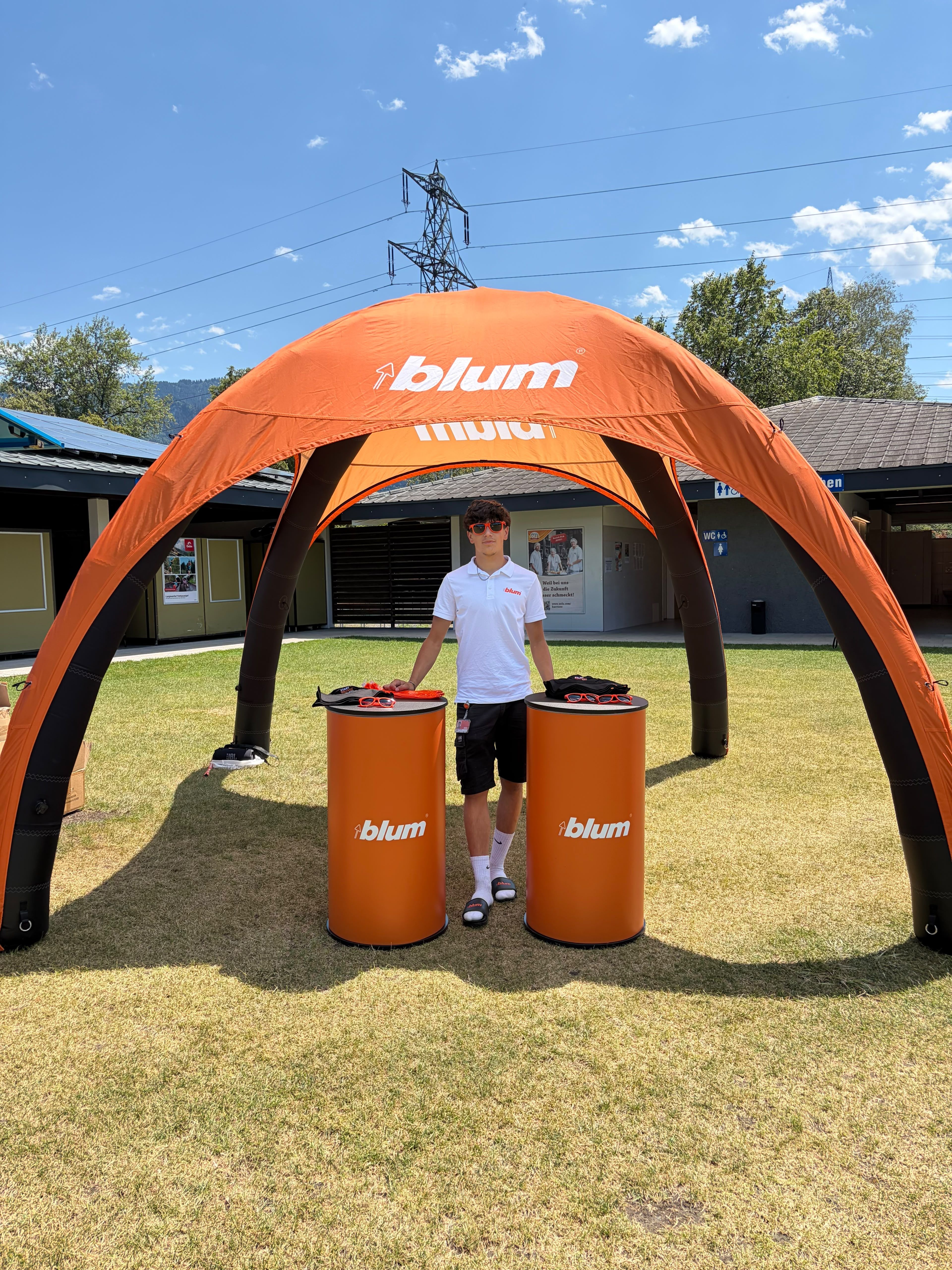 Auszubildender von Blum informiert bei der Sommertour über Ausbildungsberufe und Karrierewege. Der Informationsstand bietet Gelegenheit zum persönlichen Austausch und zu Einblicken in die Ausbildung bei Blum.