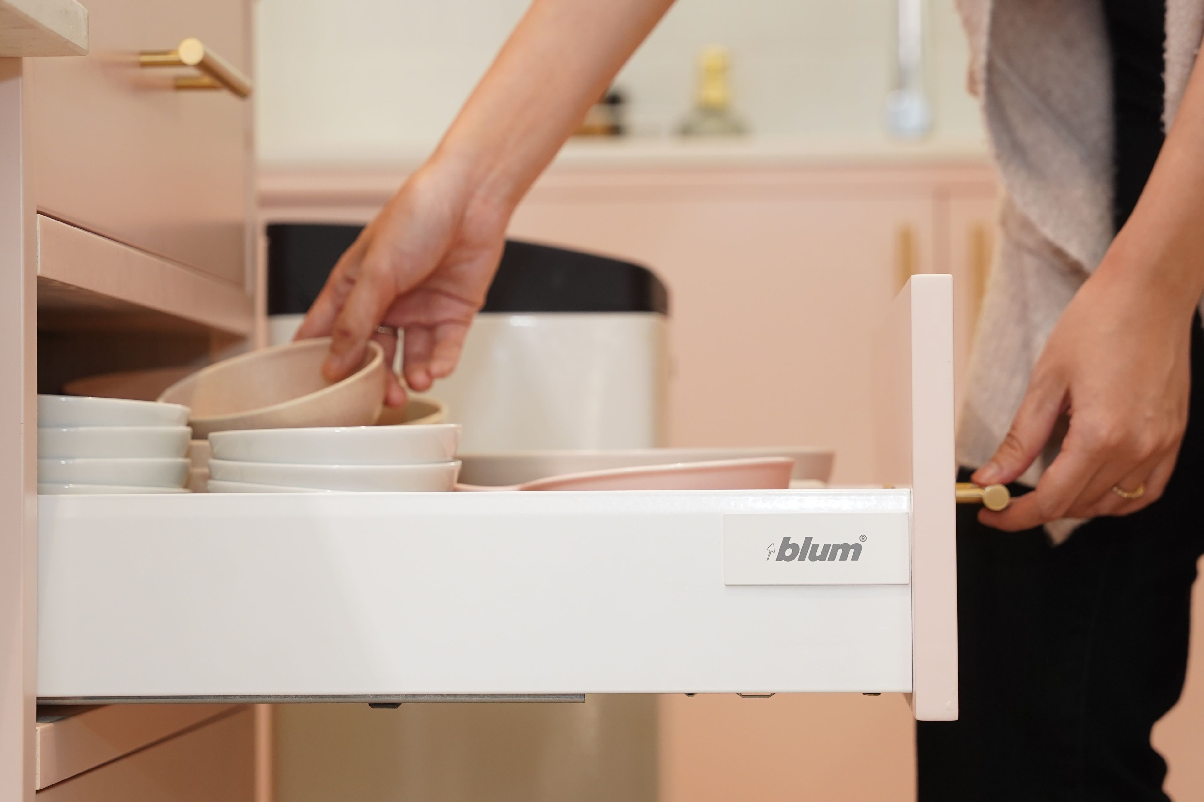 The lady opens the drawer to take out the bowl