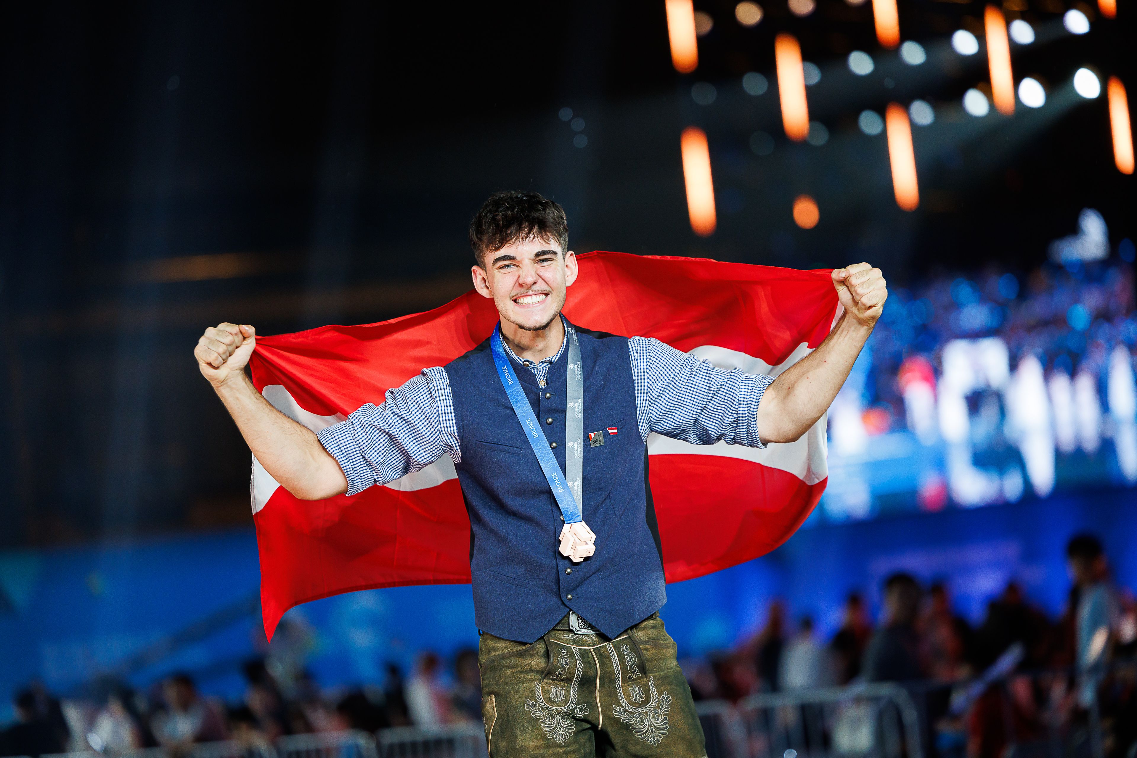Österreichischer Teilnehmer von Blum feiert mit Bronze-Medaille und rot-weiß-roter Flagge seinen Erfolg bei den WorldSkills 2026 in Shanghai.
