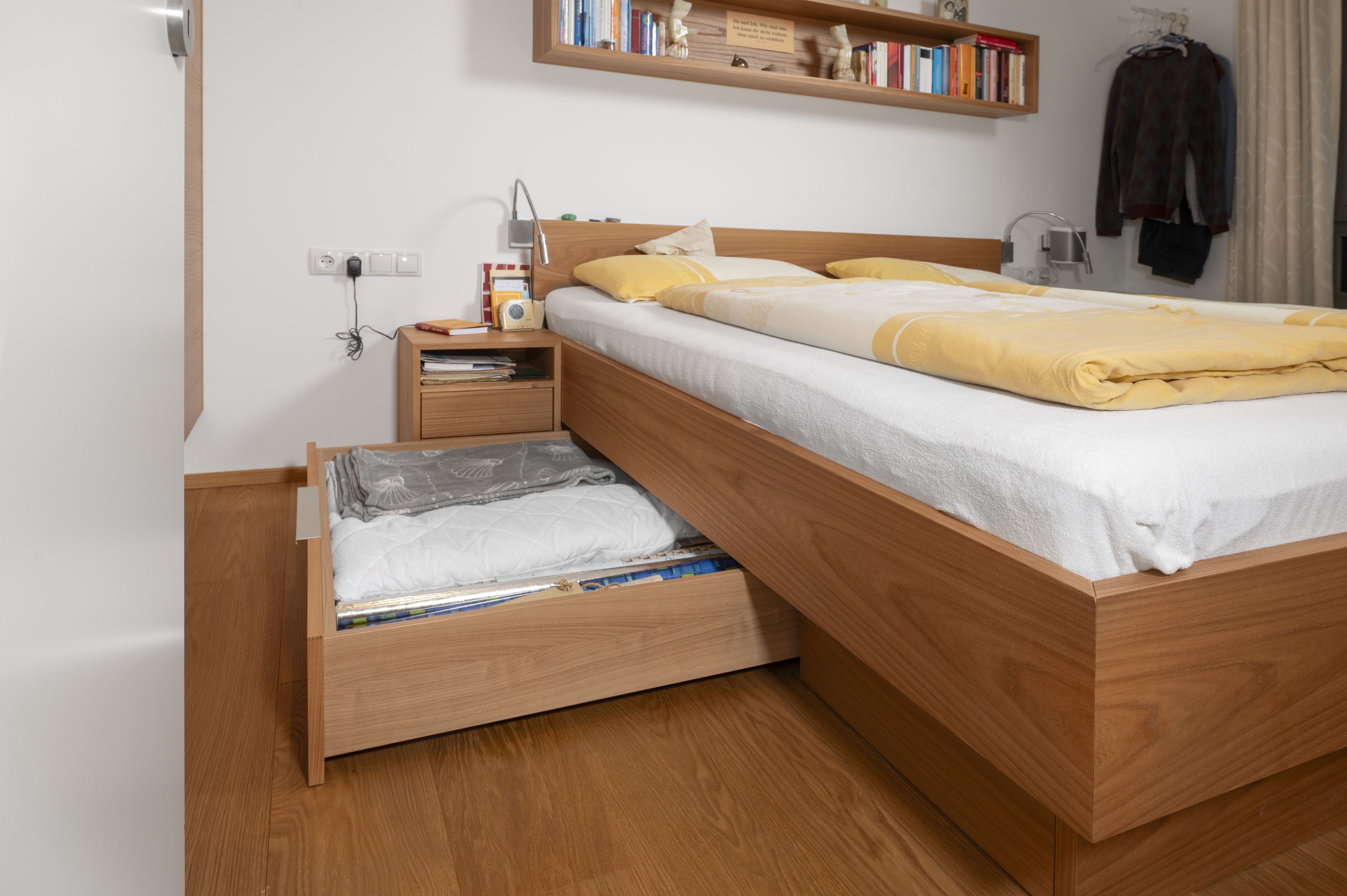 Ein Bett mit einer geöffneten, großen Bettschublade unter der Matratze