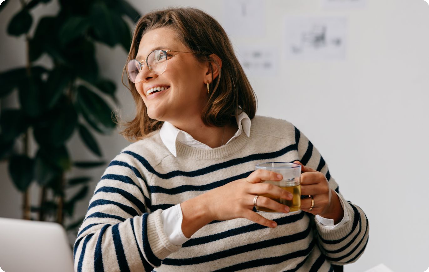 Smiling woman with glasses holding a glass illustrating Atlas HXM Direct Employer of Record