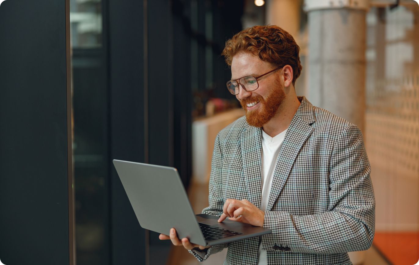 Smiling man using a laptop illustrating Atlas HXM Agent of Record