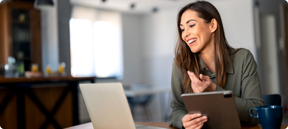 A woman with a cheerful expression uses her laptop, reflecting a productive moment.