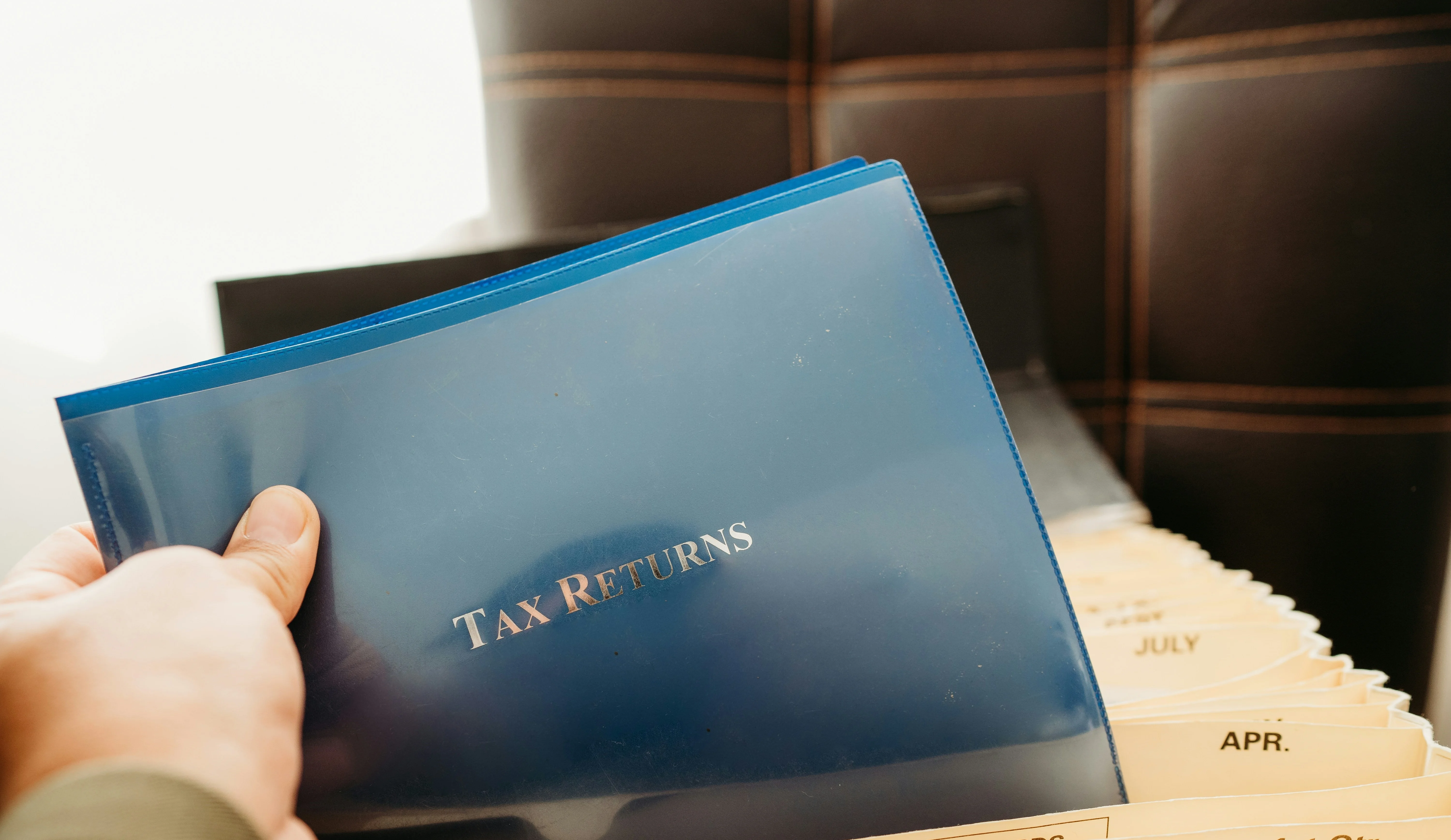 Hand holding a blue folder labeled 