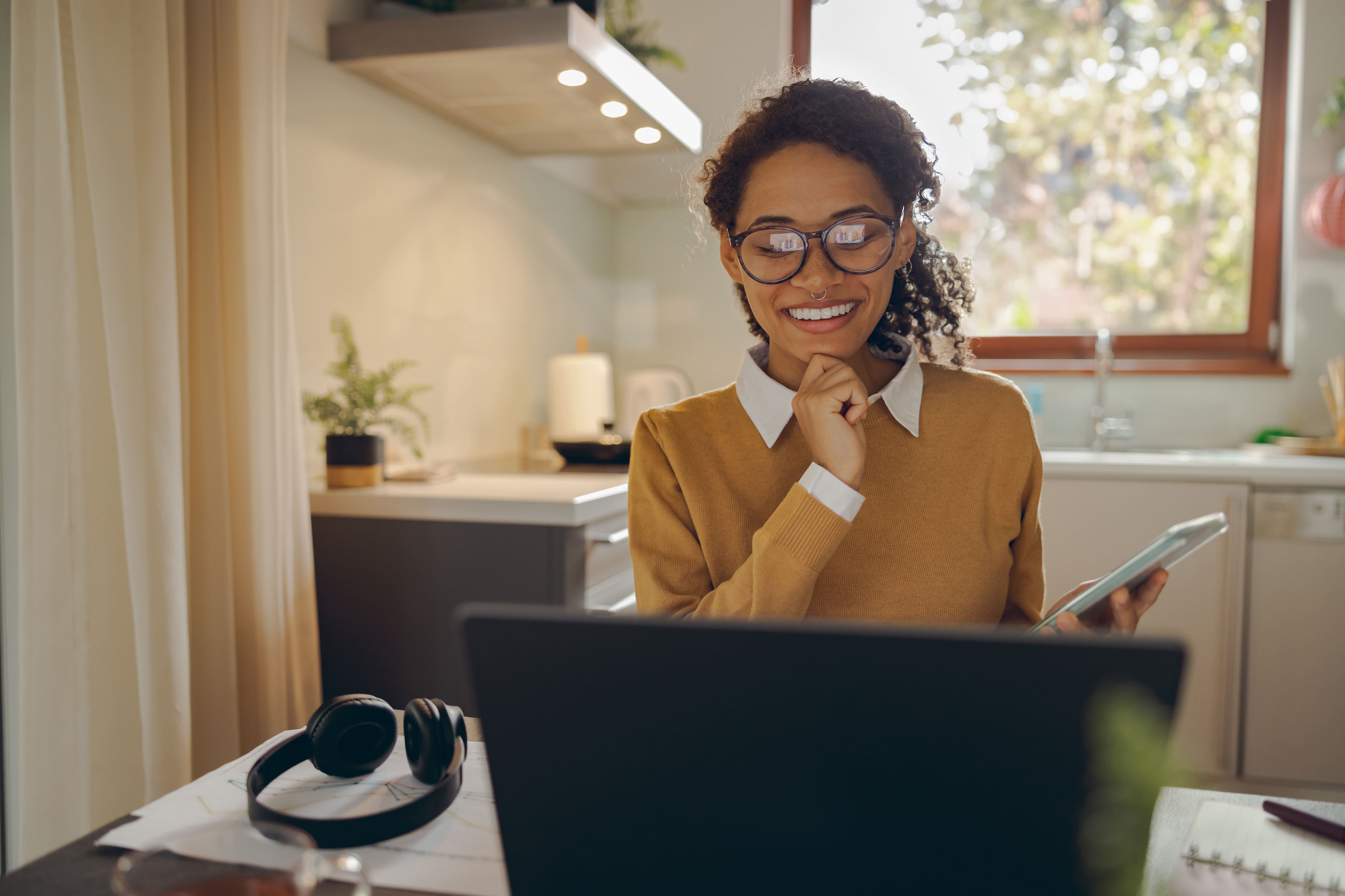 smiling woman is use smartphone while working laptop from home distance work concept