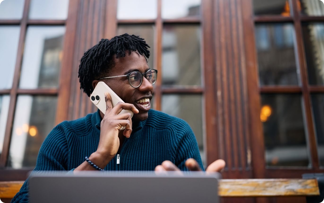 Man with glasses using a laptop while on a phone call illustrating Atlas HXM Global Mobility Services