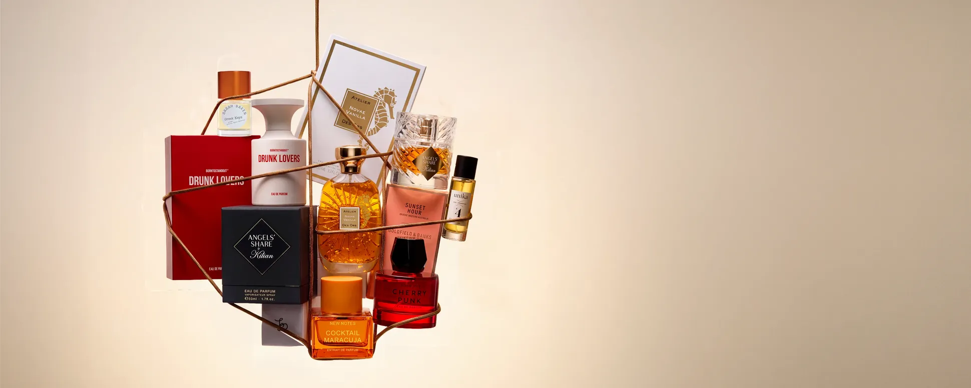 A collection of various perfume bottles artfully arranged with boxes and ribbons, set against a soft beige background.