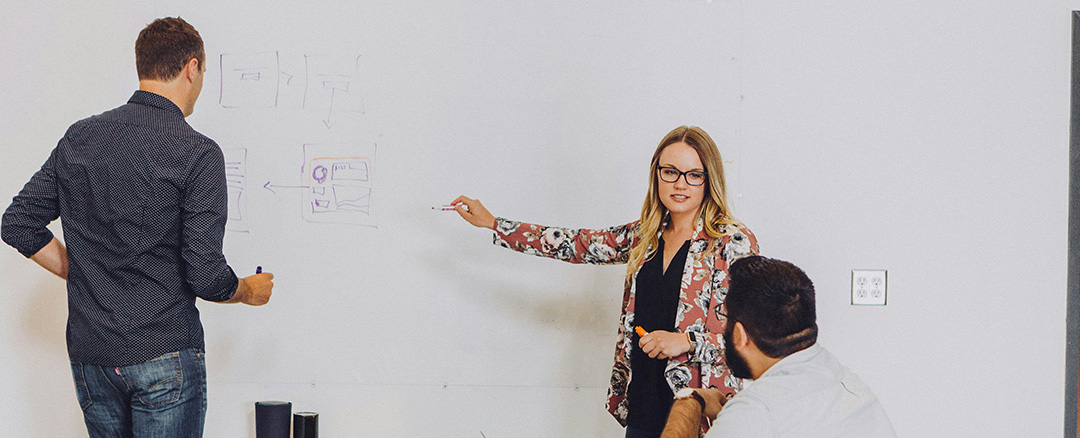People writing on a whiteboard with markers during a meeting, illustrating natural and intuitive collaboration without touchscreen interaction
