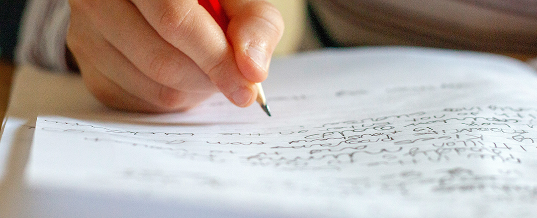 Person writing by hand with a pencil on paper, illustrating creativity, cognitive processing, learning and natural human expression.