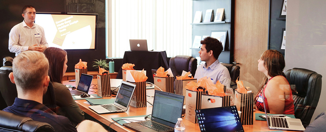 Team attending a presentation in a conference room with a display screen, illustrating traditional AV setup focused on screens rather than collaboration workflows