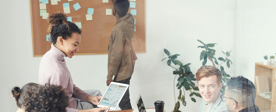 Modern Collaborative Workspace for Creative Team Meetings Team collaborating in a modern office space using a tablet and whiteboard with sticky notes, ideal for brainstorming sessions, project management and innovation workshops.