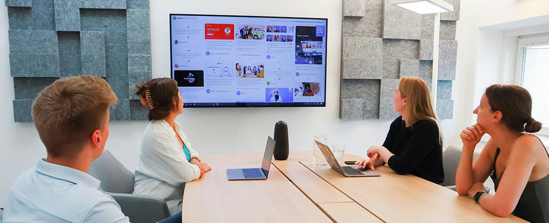 Group of people watching a large screen in a meeting room, highlighting low interaction and limited engagement in screen-based collaboration