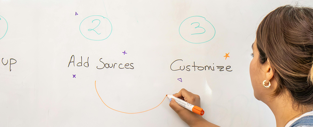 Person writing whiteboard A person writes with an orange marker on a whiteboard displaying simple handwritten steps and doodles, focusing on customization and creative planning.