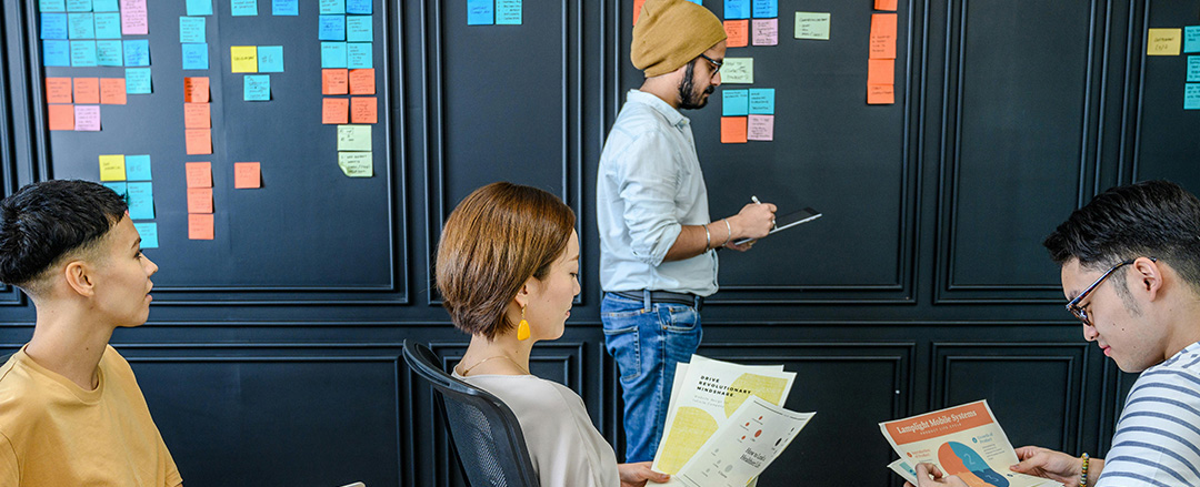 Team using sticky notes on collaboration wall illustrating analog brainstorming captured for hybrid collaboration environments