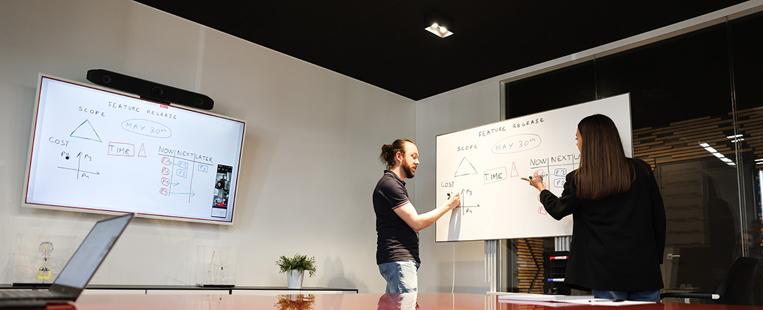 Employees planning hybrid work schedules on a digital whiteboard in a meeting room