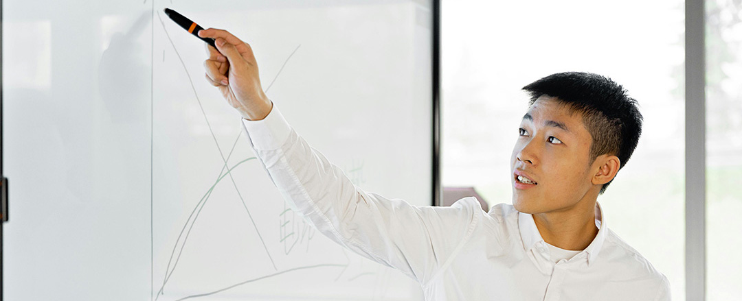 Educator writing on a digital whiteboard with a stylus, demonstrating interactive teaching, edtech adoption, and real-time content sharing in modern classrooms