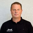 Man in a black polo shirt with "Altitude" logo stands against a light gray background, looking directly at the camera.