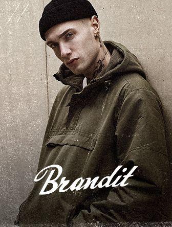 Person in a green jacket and black beanie leaning against a wall, with "Brandit" text overlayed at the bottom.