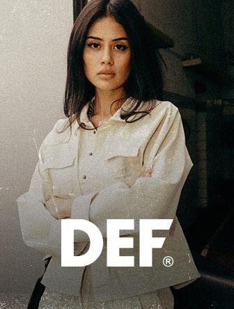 Woman with long hair wearing a light jacket stands with arms crossed. "DEF" text is displayed at the bottom.