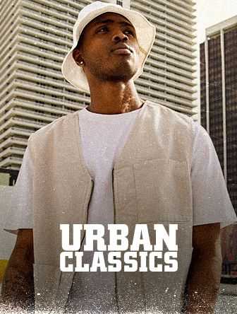 Man in a white bucket hat and vest stands in front of tall buildings, with "Urban Classics" text overlay.