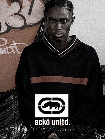 Person wearing a dark Ecko Unltd. sweater stands in front of graffiti art.