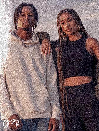 A man in a hoodie stands beside a woman in a black top and braids, with her arm on his shoulder, set against a cloudy sky backdrop.