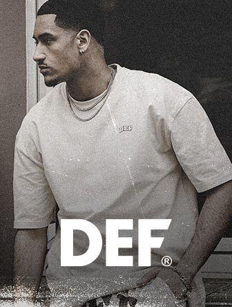Man in a casual DEF t-shirt leans against a surface, gazing to the side. The image has a vintage, textured appearance.