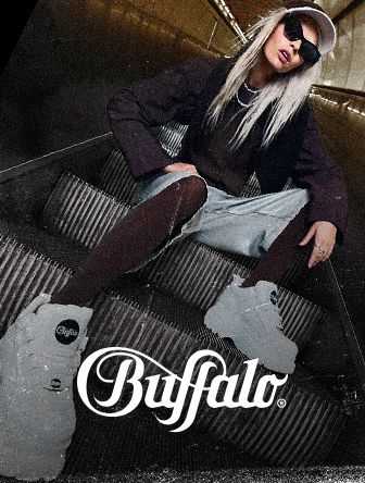 Person with long hair wearing sunglasses, sitting on an escalator in trendy attire, sporting white Buffalo platform shoes. Buffalo logo at the bottom.