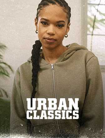 Person in a gray hoodie with braided hair stands indoors. Text reads "Urban Classics."