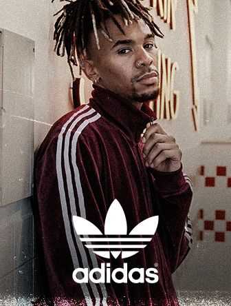 Man in a red Adidas tracksuit poses with a thoughtful expression, standing against a wall with retro-style graphics.