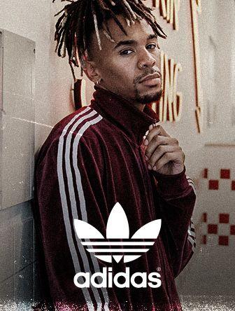Man in a red Adidas tracksuit poses with a thoughtful expression, standing against a wall with retro-style graphics.