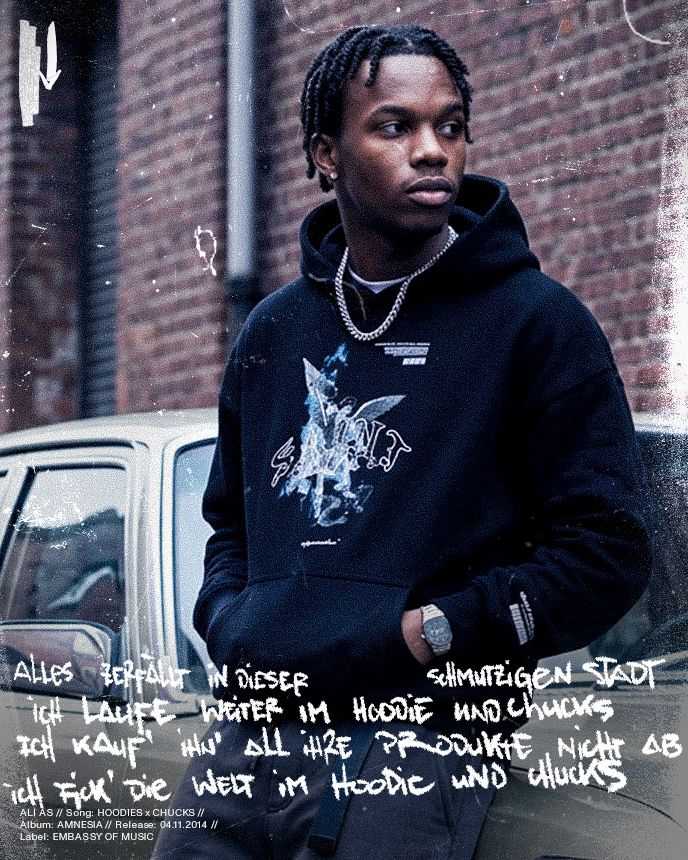 Man in a black hoodie with chain necklace leans against a car in an urban setting. Handwritten text overlays the image.