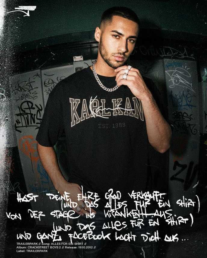 Man in a Karl Kani shirt and chain stands against a graffiti-covered wall, with stylized text overlay about selling out.