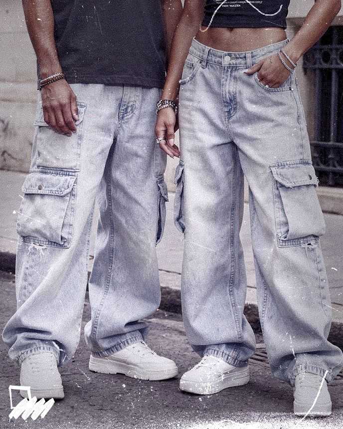 Two people in oversized light-wash cargo jeans and white sneakers stand on a street, showing only the lower halves of their bodies.