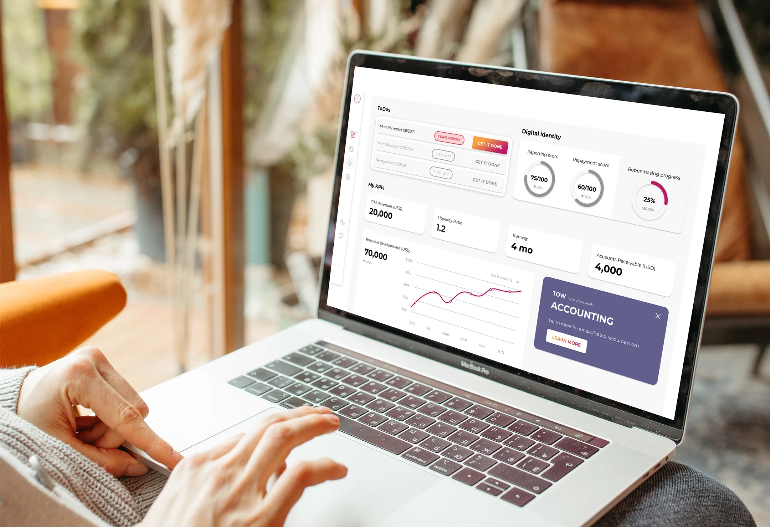 Picture of person using a MacBook on their lap. On the screen is a view from the Uncap investment platform with several sections, numbers, and a chart.